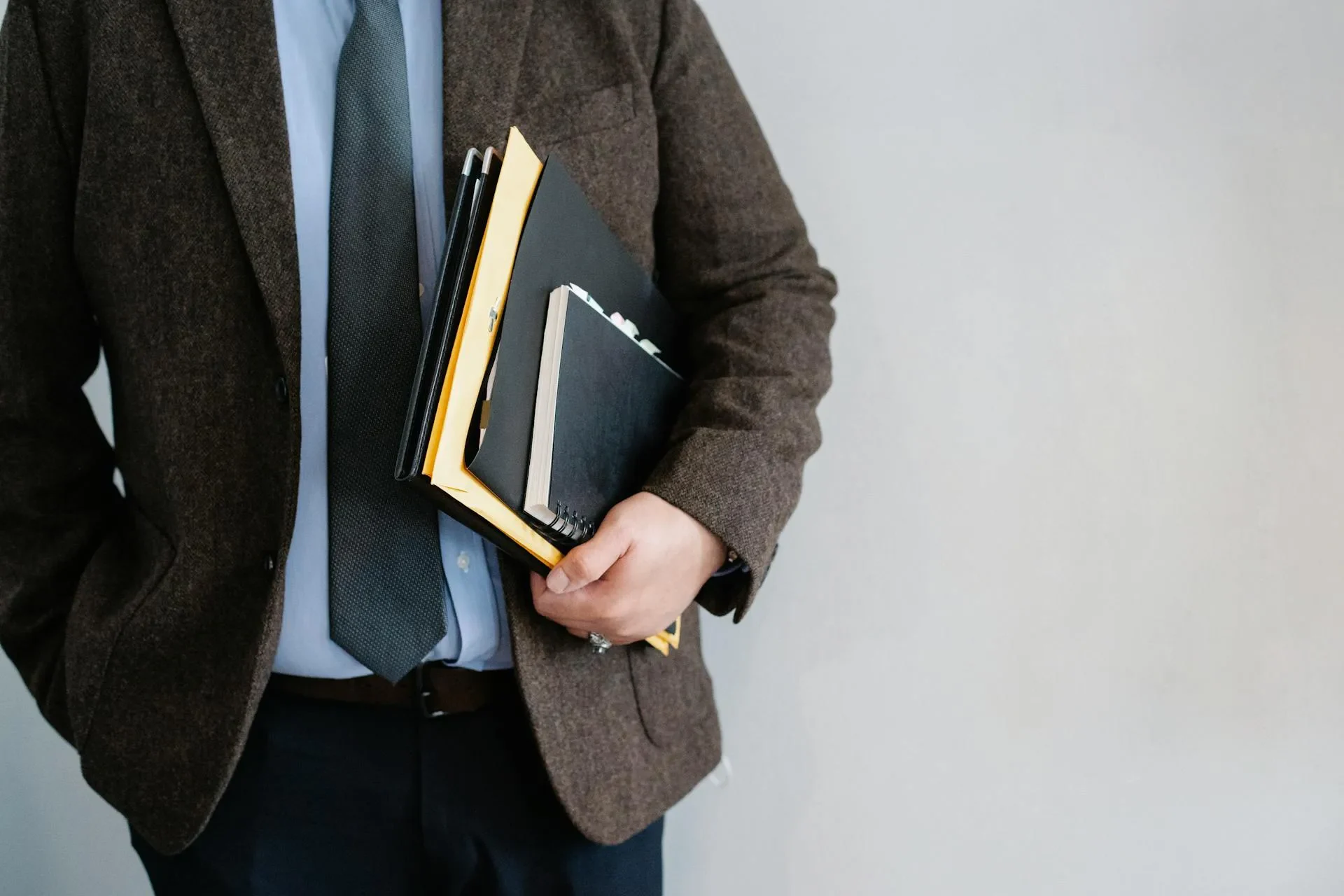 un homme en costume tenant des dossiers et carnets.