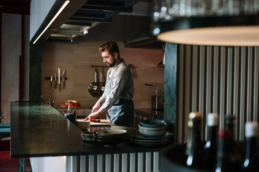 Chef cuisinier coupant des légumes sur un plan de travail dans une cuisine professionnelle.
