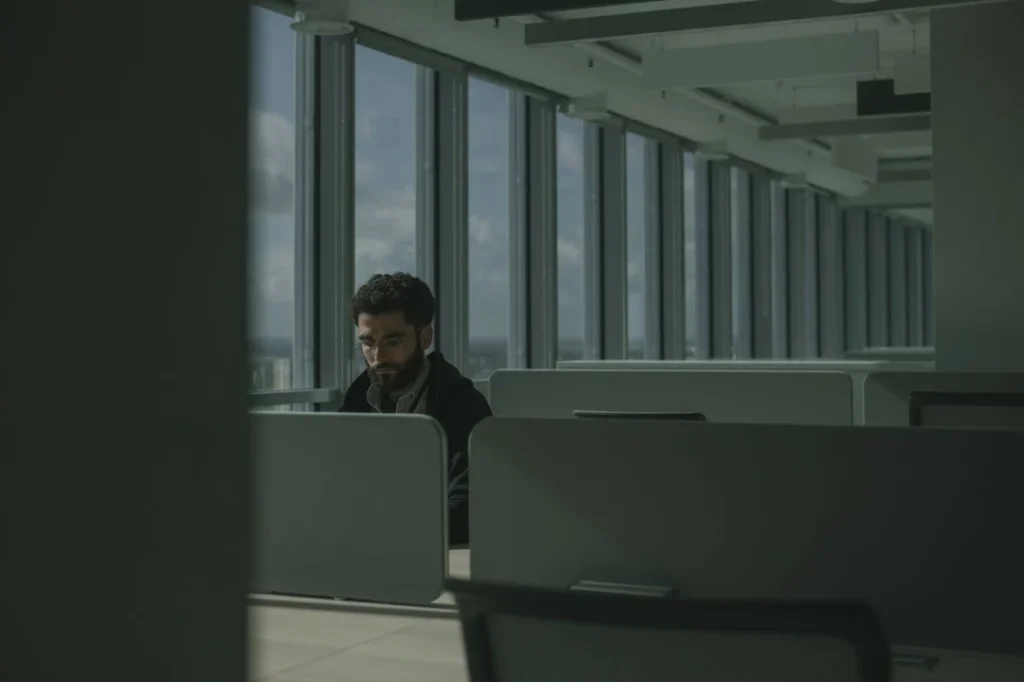 Salarié travaillant seul dans un open space, concentré sur son poste de travail, sans interaction directe avec ses collègues.