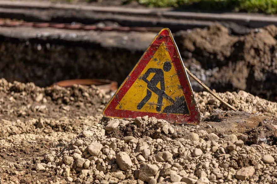 Panneau de signalisation indiquant des travaux en cours, placé au sol sur un chantier. L’image illustre la présence de risques et la nécessité de prévention et de vigilance dans un environnement de travail.